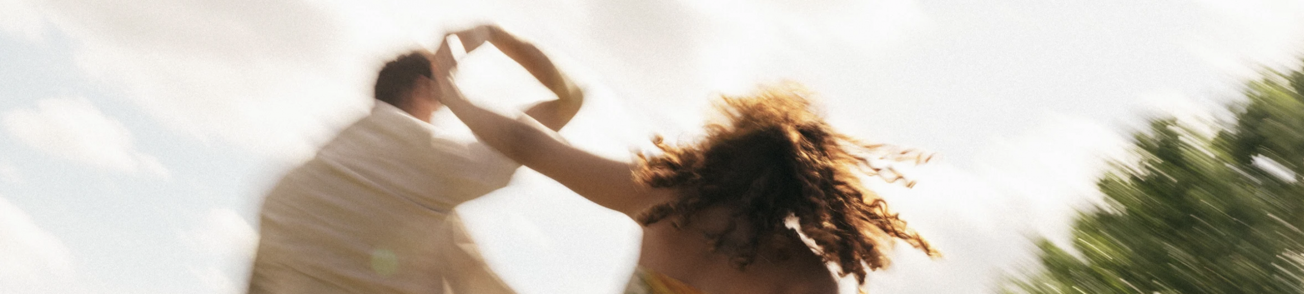 Image banner of couple dancing outdoors in summer sunlight, symbolising connection, joy, and movement in a healthy relationship