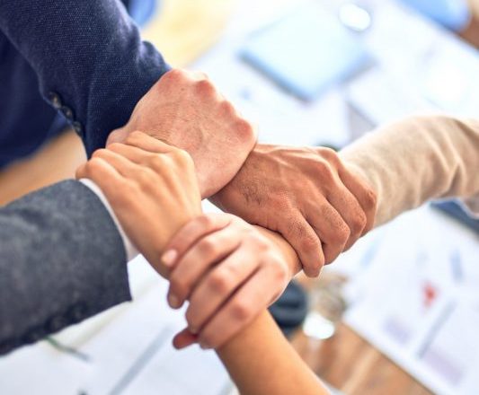 Four arms and hands interconnected in a group, symbolising collaboration and support in supervision for trainee counsellors.